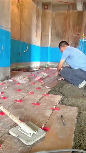 Man installing ceramic floor tiles using leveling spacers