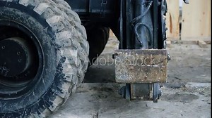 Close-up heavy industrial wheeled excavator extracting outrigger support balance arm for stabilization before moving ground at building construction site
