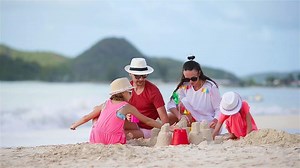 Parents with kids play making sand castle at tropical white beach