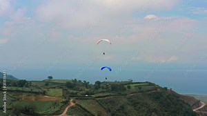 Amazing aerial video of flying paraglider on the background of wild nature. Paraplan drifting above the green tropical trees. Extreme sport. Hipster modern hobby concept. Paraplane flying in the sky.