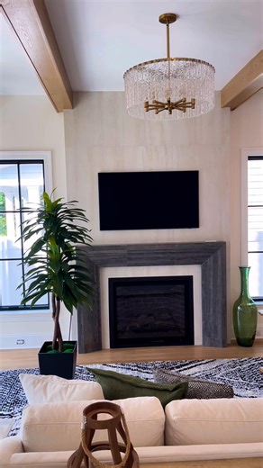 Custom fireplace installation using large-format 24x48 tiles arranged vertically to create a modern and stylish finish. The design features a frame constructed from dark gray tiles with a wood-grain finish, adding character, elegance, and a unique contrast to the main wall. This fireplace completely transforms the space, offering a contemporary, clean, and comfortable style that enhances the entire living room area. #FireplaceRemodel #FireplaceDesign #ModernFireplace #TileInstallation #24x48Tile