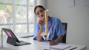 Medical professional explains human spine model during virtual consultation, providing detailed anatomical information to patient through online video call