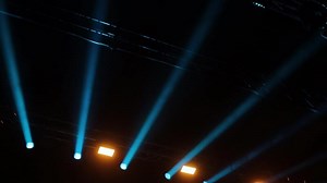 Download Vibrant stage lights beam across a dark venue of rock concert. Blue and white stage lighting illuminates the night during a live performance. Light effects in the darkness of a live music event for free