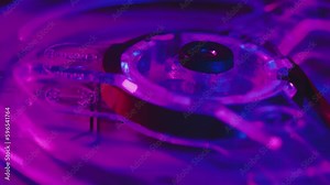 Close-up of a transparent reel rotating on a vintage analog tape recorder. Bobbin with retro tape in the light of the club violet-pink lights