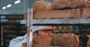 Good looking chef baker smelling very enthusiastic the fresh organic bread with pleasure she take some bread from the shelf and go