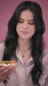 Young woman biting a donut on a pink background - Free Stock Video
