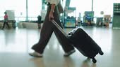 Unrecognized female passenger dragging a suitcase along the airport...