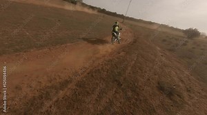 Fast FPV drone catches up to motorcycle moto racer on sandy dirt track