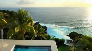 The private pool of a cliffside villa surrounded by tropical foliage and looking out over the ocean waves crashing below.