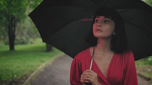 Girl with an umbrella walking through a park - Free Stock Video