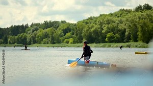 Young boy is canoeing on a large lake near a forest. Waterscape with people kayaking