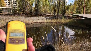 Download Chernobyl, Ukraine, 2019 - Close up of hand holding Geiger counter out of focus showing radiation levels by the pond in Chernobyl contaminated exclusion zone.