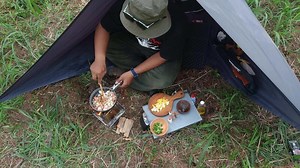 A man in a hat cooking food in a tent