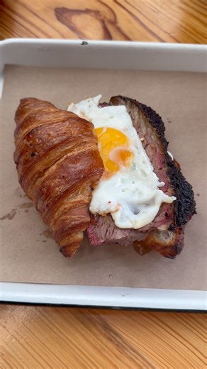 The Blue October from Burnt Bean Co. is the GREATEST Breakfast Sandwich of ALL TIME! It starts with a perfect croissant 🥐, topped with jalapeño cream cheese, then PERFECT Texas Brisket, a sunny side up egg, and topped with strawberry jam. Perfection. #bbq #grill #burntbeanco #breakfast | Gulf Coast Smoke