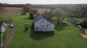 Drone shot and aerial of an old, wooden barnyard farming building and rural barn in the outskirts of a midwestern town in Ohio, not far from Danville, OH