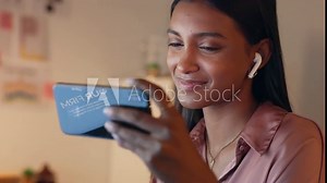 Woman on video call, with phone and headphones has bad audio connection. Latino girl in video conference or watching video on social media has network glitch, try to adjust headset for better sound Stock Video