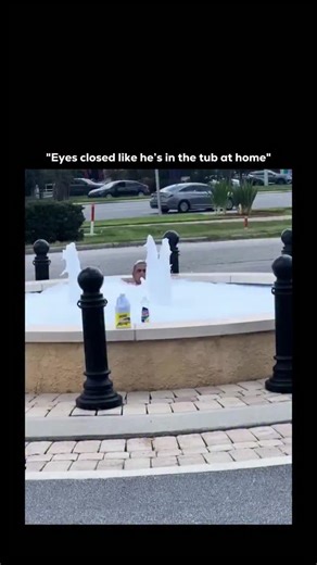Learnify Society™ on Instagram: "This video features a humorous and bizarre scene of a man using a public decorative fountain as his own personal bubble bath. A man is seen sitting comfortably inside a public water fountain. The water is overflowing with thick white foam, likely caused by someone pouring soap into the fountain's circulation system. On the edge of the fountain, there are bottles of Ajax dish soap and Bleach, implying the man (or someone else) deliberately turned the fountain into