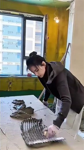 Woman worker preparing to install large white floor tiles in a construction room