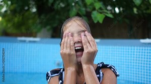 Sweet little girl having fun in the pool splashing in the water spraying it in different sides. Happy childhood, summer vacation