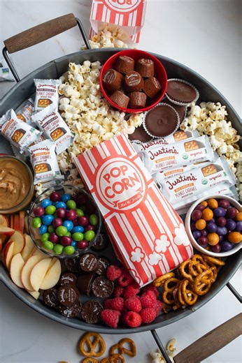 Summer blockbuster double feature: a JUSTIN'S® Candy Bars in one hand and popcorn and Chocolate Candy Pieces in the other. #movienight | Justin's