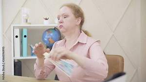 Caucasian redhead woman suffering from climacteric changes. Senior lady having hot flashes and waving fan. Femininity, female aging, health care problems, gynecology, menopause.