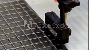 A close-up view of an industrial tool measuring a metal plate in a manufacturing setting. This image highlights the precision and technology used in modern industrial processes