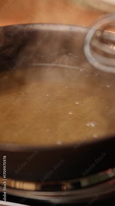 A pot of food is being stirred with a whisk. The steam rising from the pot creates a cozy atmosphere