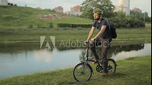 Man on bicycle riding to the park with laptop