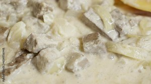 beef liver cooking, braising liver sauce in a skillet with onions and sour cream, slow motion video, sauce