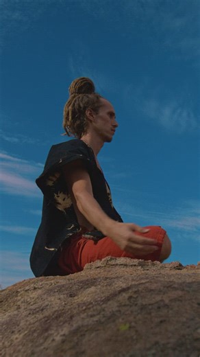 Meditating man sitting on a rock outdoors - Free Stock Video