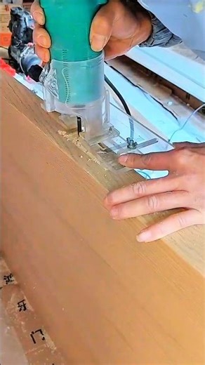 Router trims wood edge clean—green casing hums as hands guide groove through shavings on busy bench.