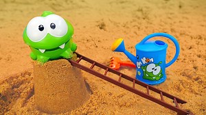Nuevos dibujos animados de OmNom español. Hoy veremos los nuevos vídeos de juegos con las formas de arena. Om Nom va a construir un castillo de arena y para ello tendrá la ayuda del camión. ¡Mira cuánta arena ha traído! Om Nom, coge la pala y los moldes. Y para que las formas de arena salgan bien, hay que mezclar la arena con un poco de agua. ¡Así mucho mejor! Pero Om Nom quiere hacer algo más grande... ¡Un castillo! | Dibujos animados y Vídeos para niños