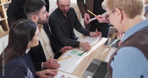 Team coworkers meeting in office reviewing charts. Hands pass documents and pencils across a desk as managers align targets and plan budgets. Clear teamwork, planning, and analysis concept.