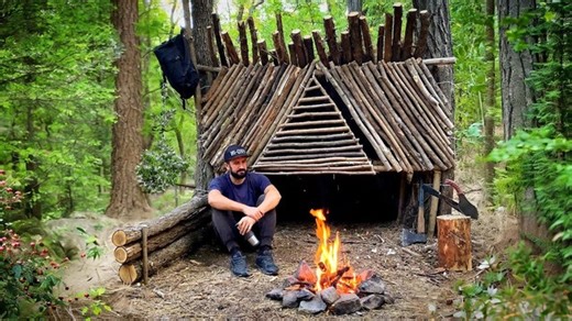 Solo builds a small temporary shelter between two trees in the forest. | Complete Bushcraft