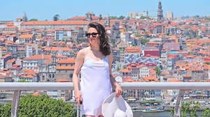 Woman tourist with hat travel bag enjoying cityscape of Porto City, Portugal
