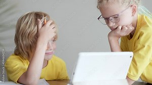 Sister helps little brother do school homework at home, Distance learning online education, boy and girl studying at home with digital tablet.