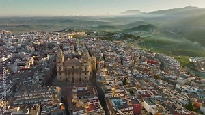 Aerial view of Jaen Cathedral early in the morning. Jaen, Andalucia, Spain with foggy green hills at background. UHD, 4K.