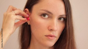 Young woman shows how to correctly insert earplugs into noise protection.