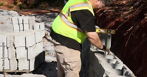 An installation of newly constructed large block retaining wall by contractor in construction site during construction phase