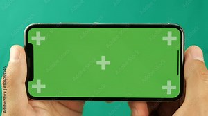 Horizontal smartphone in the hand closeup isolated at green background. Phone screen is green chroma key, background with another chroma key green screen. Footage for mobile ads, app promo.