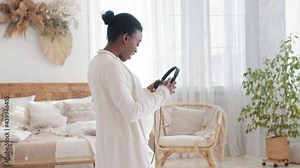 Afro american woman african black ethnic expectant mother listening to music song melody enjoying pregnancy dancing taking off headphones from head putting on pregnant belly audio therapy unborn baby