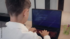 Portrait of child prodigy boy is programming the code behind a laptop at home. Young hacker works at a computer.