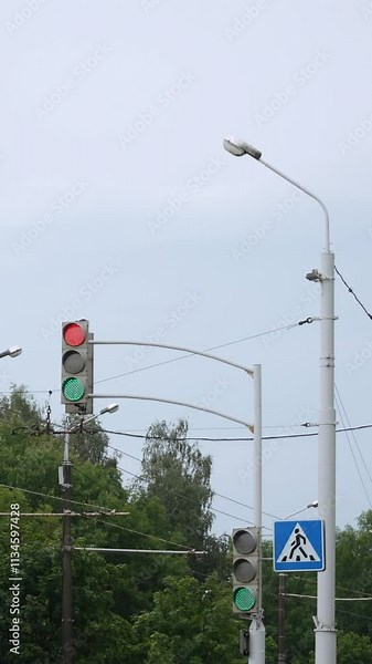Vertical video of broken road flickering traffic light at intersection with pedestrian crossing with two opposite signals. Red prohibitory and green permissive light during software failure outdoor.