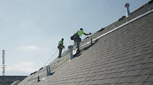Wide panning low angle shot of workers installing rails on roof / Mapleton, Utah, United States