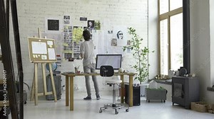 Smart professional working in his office studio. Planning his schedule and timetable: tasks, meetings, reviews, deadlines. He makes notes and stick them to the wall marking important information.