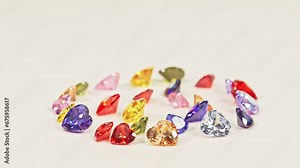 .Beautiful multi-colored heart-shaped diamonds set in a circle..Heart-shaped diamonds in various colors are set on white floor..The sparkling light of diamonds looks charming and beautiful.