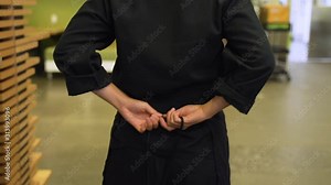 This shows a chef putting on an apron in order to safely cook in the kitchen.