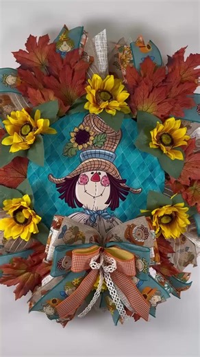 Bring a touch of farmhouse charm to your front porch with this handmade fall scarecrow wreath, overflowing with bright sunflowers, rustic autumn leaves, and a cheerful scarecrow centerpiece. Perfect for welcoming guests all season long, this vibrant wreath combines shades of golden yellow, burnt orange, and teal for a stunning fall display. A large, multi-layered bow featuring adorable scarecrow and pumpkin ribbon adds the perfect finishing touch.