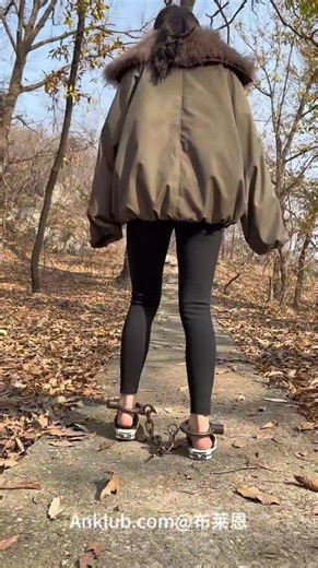 A girl is walking through the mountains wearing shackles.|女生戴镣户外