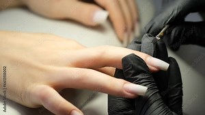 Female hands and tools for manicure, process of performing manicure in beauty salon. Nail care procedure in a beauty salon. Gloved hands of a skilled manicurist cutting cuticles. Concept spa body care